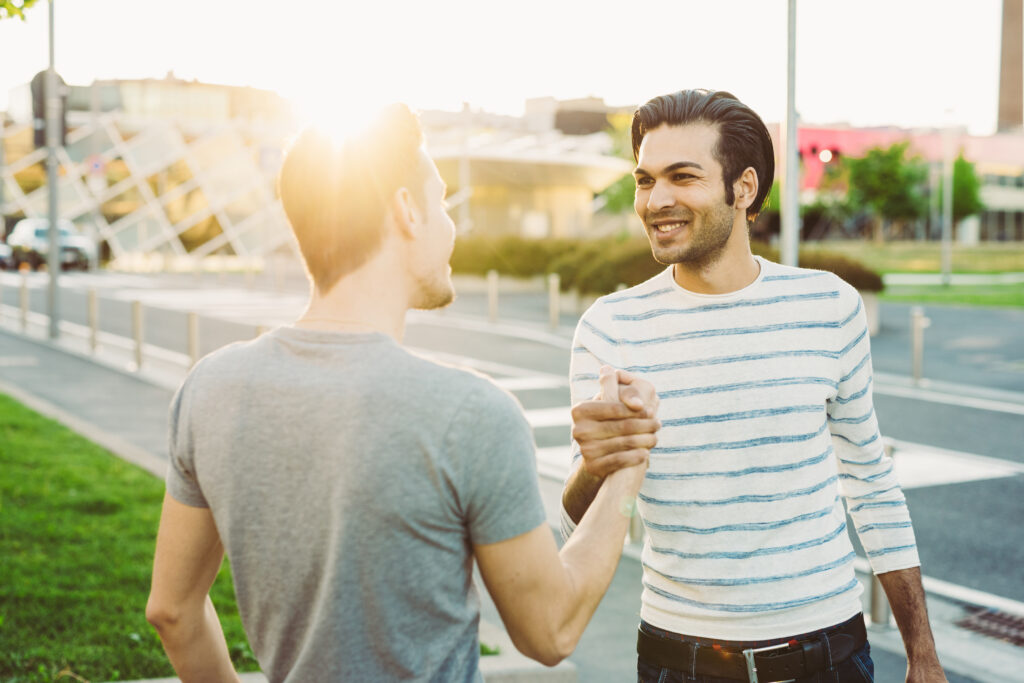 Two multiethnic friends hand shaking back light