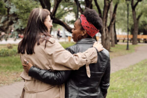 Back view of young cheerful females interacting during walk in park